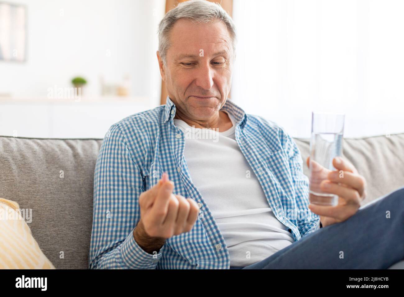 Homme mature prenant des pilules tenant un verre d'eau Banque D'Images