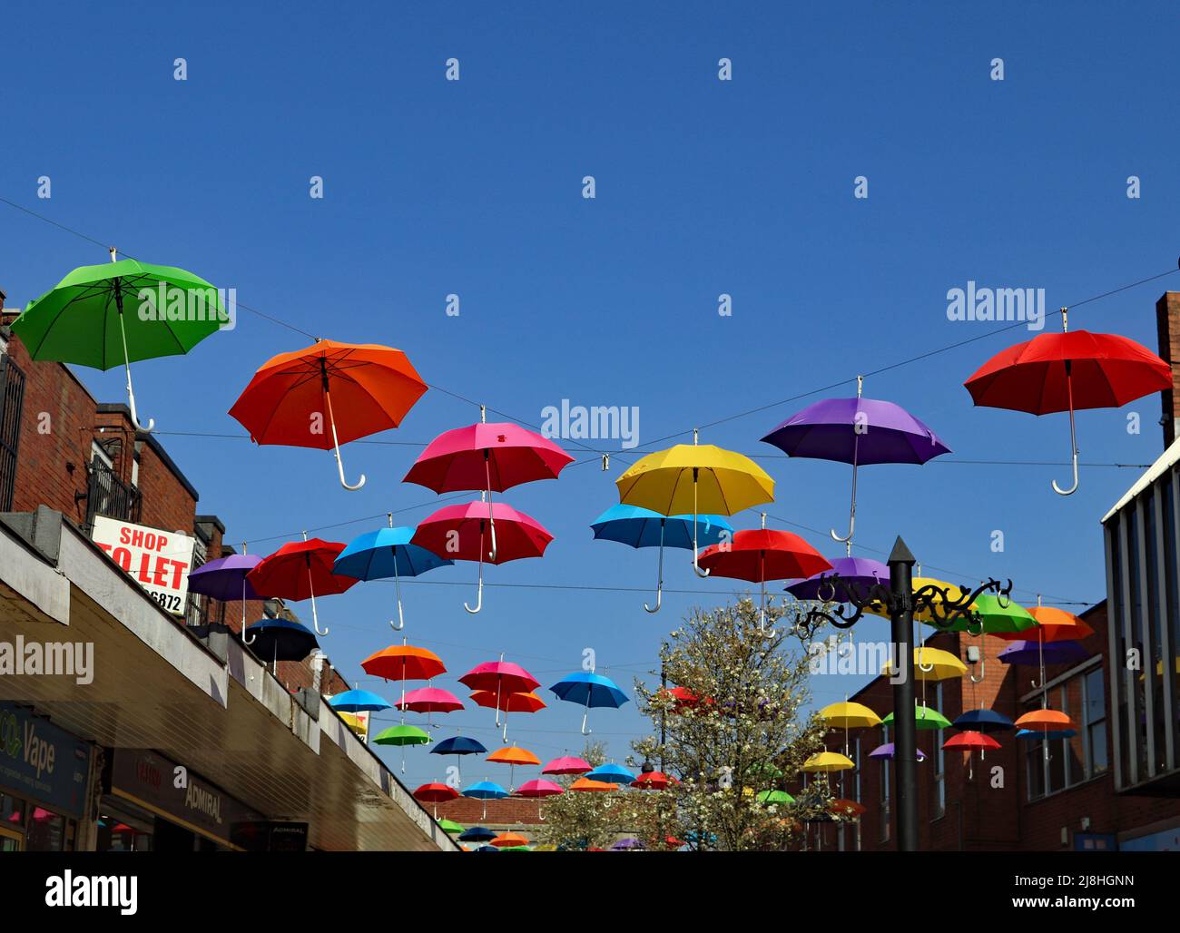 Une exposition colorée de parasols a été installée sur une voie piétonne dans le centre commercial d'Alfreton, dans le Derbyshire. Banque D'Images