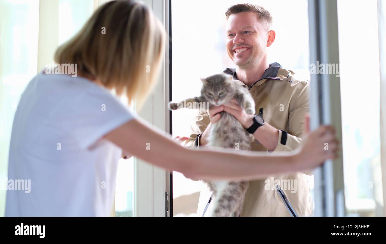 Homme donnant le chat gris à la femme par la porte Banque D'Images