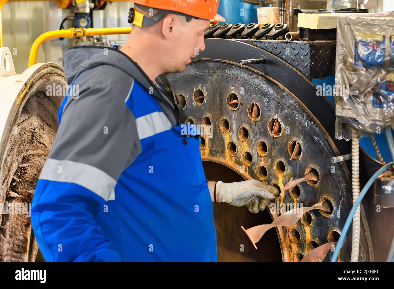 Un ingénieur en casque inspecte et répare les équipements à gaz de la chaufferie. Nettoyage et entretien de chaudière à vapeur industrielle. Banque D'Images