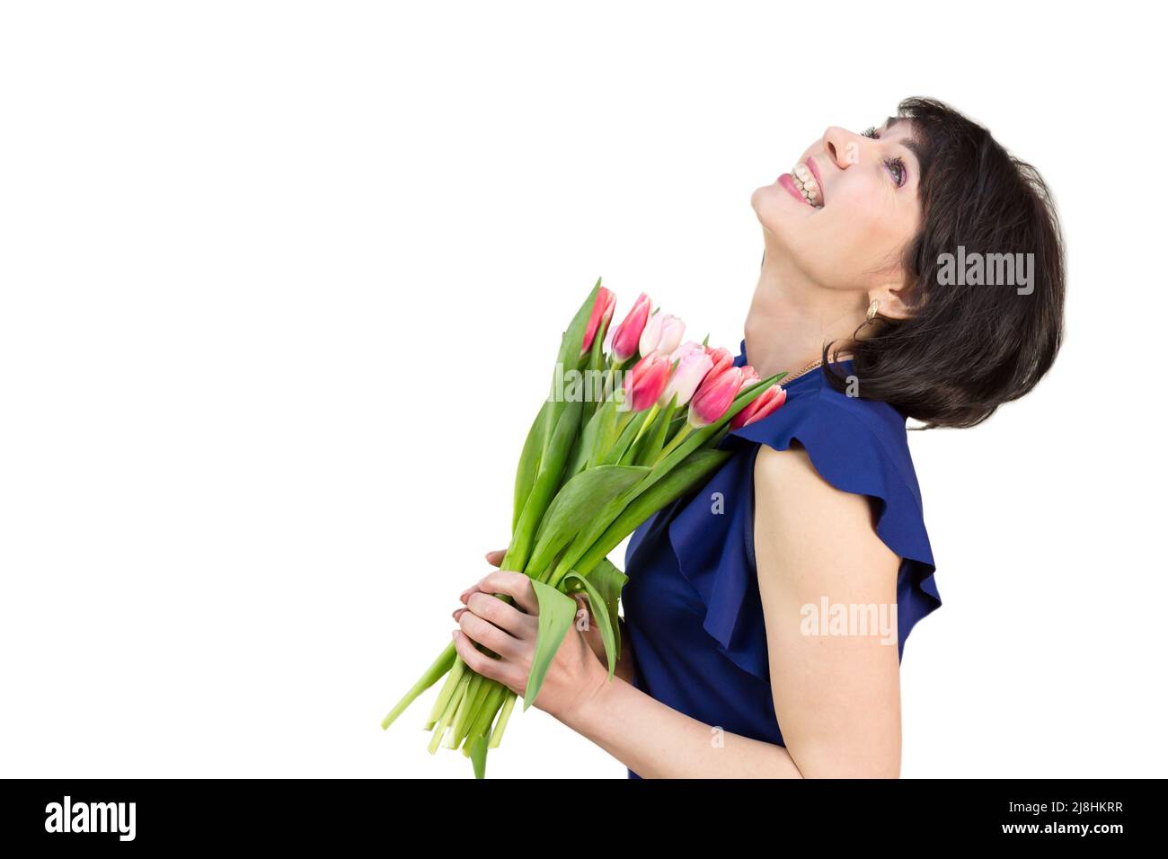 Une femme heureuse avec un bouquet de tulipes jette sa tête en arrière riant sur un fond blanc. Banque D'Images