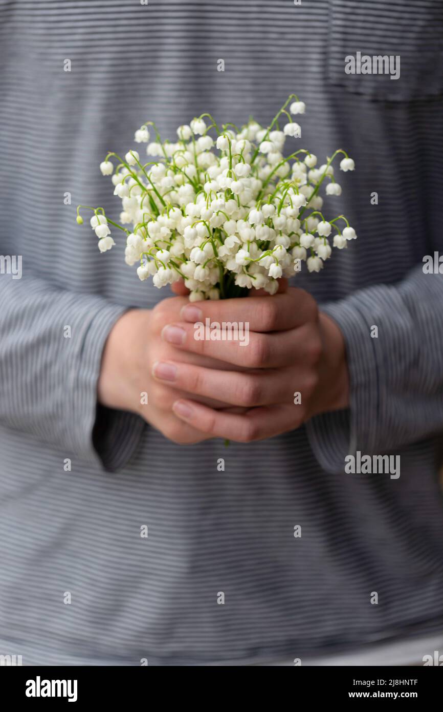 Un enfant tenant un bouquet de lis de fleurs de la vallée Banque D'Images