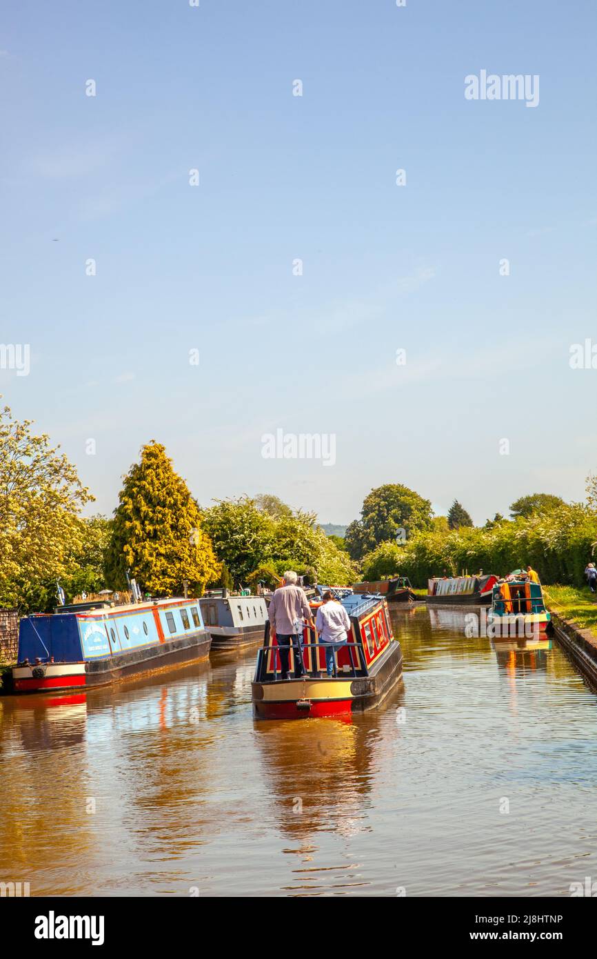 Homme et femme sur un canal loué en bateau à narrowboat passant par Hassall Green sur le canal Trent et Mersey Cheshire Angleterre Banque D'Images