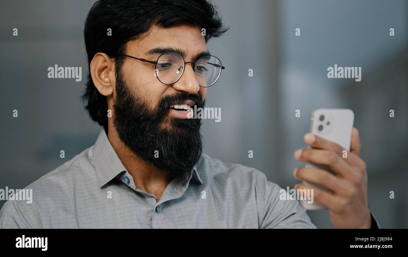 Arabian indian jeune barbu homme d'affaires beau entrepreneur tenir smartphone parlant communication vidéo en ligne avec le partenaire d'affaires virtuel Banque D'Images