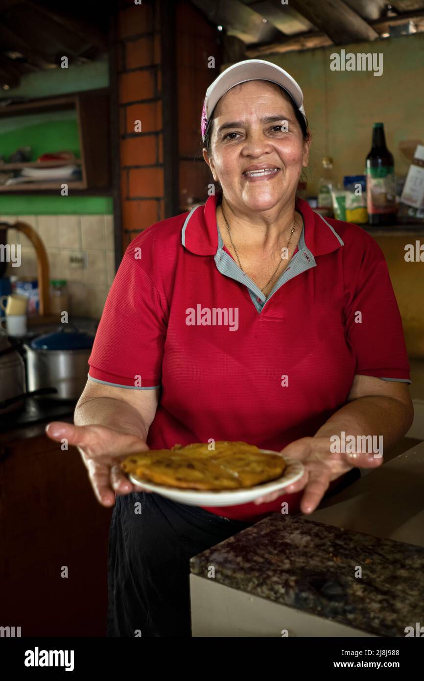 Une femme chef sourit et regarde l'appareil photo montrant une omelette fraîchement préparée dans son activité alimentaire typique du Costa Rica. Banque D'Images