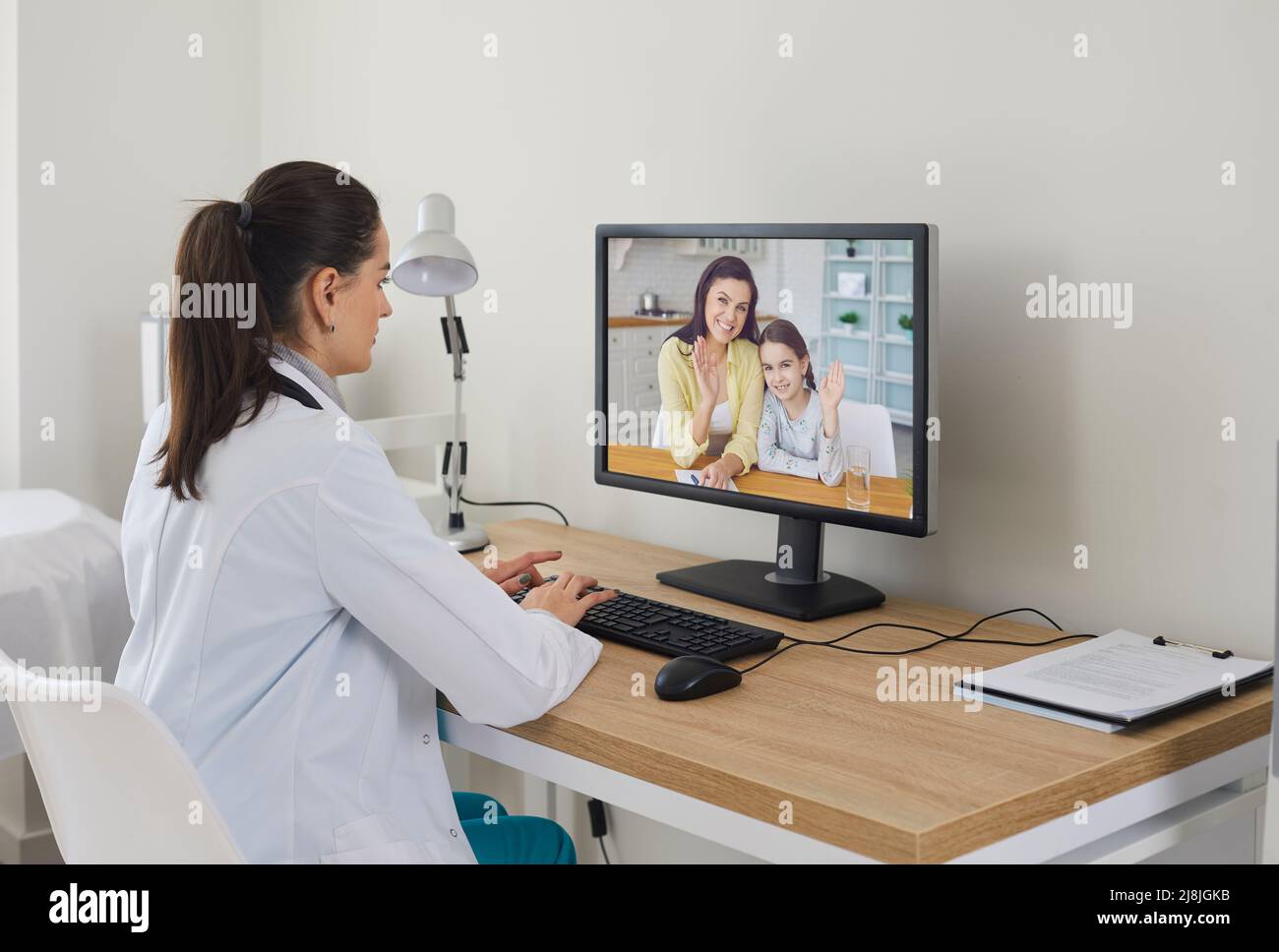 Médecin utilisant l'ordinateur et donnant la consultation en ligne de télémédecine à la famille heureuse Banque D'Images