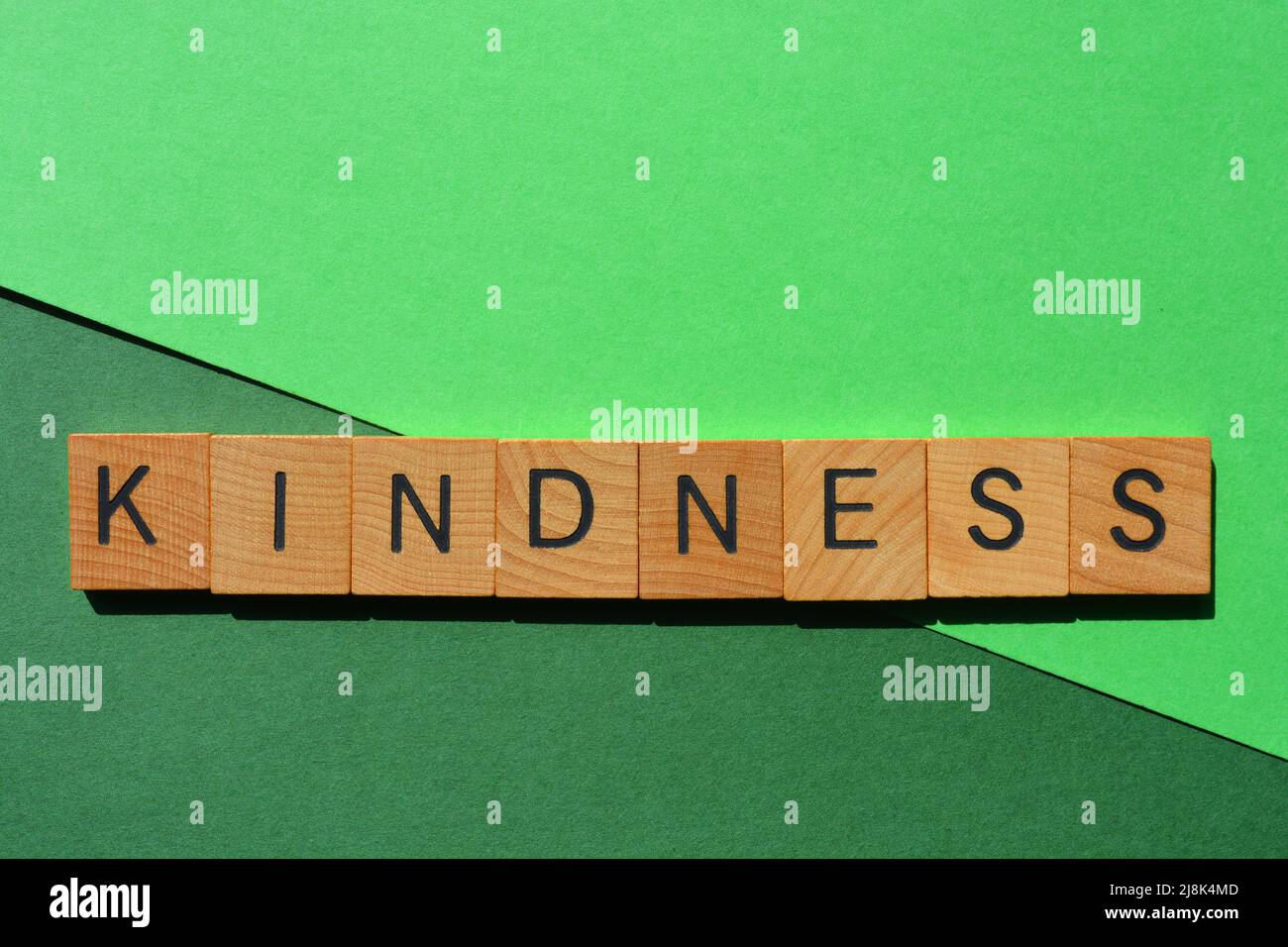 Gentillesse, mot en lettres de l'alphabet en bois isolées sur fond vert Banque D'Images