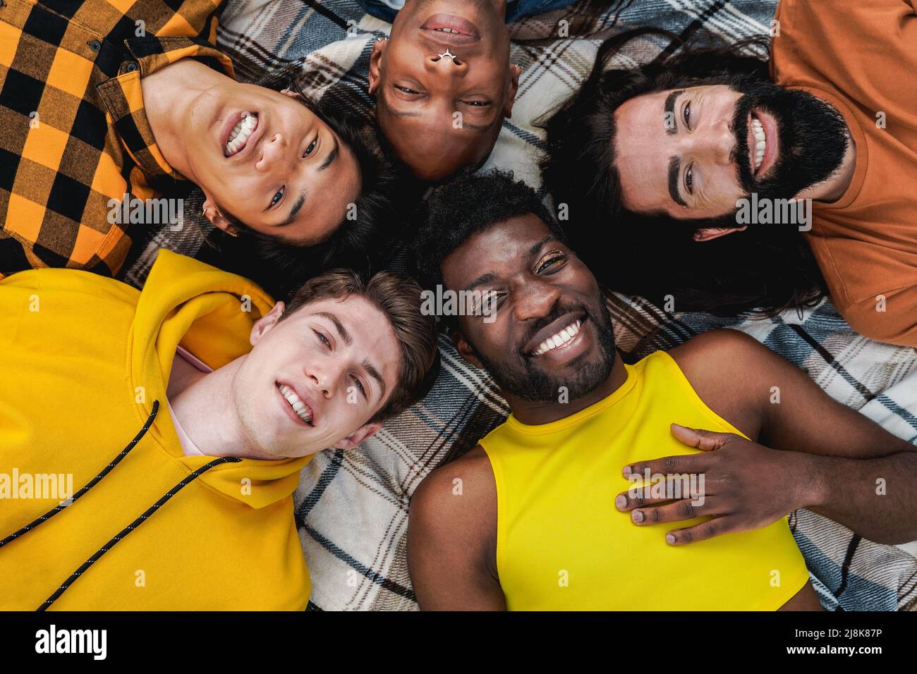 Groupe d'amis branchés divers s'amuser ensemble en plein air allongé en cercle - diversité et personnes multiethniques - se concentrer sur l'homme gay avec maquillage Banque D'Images