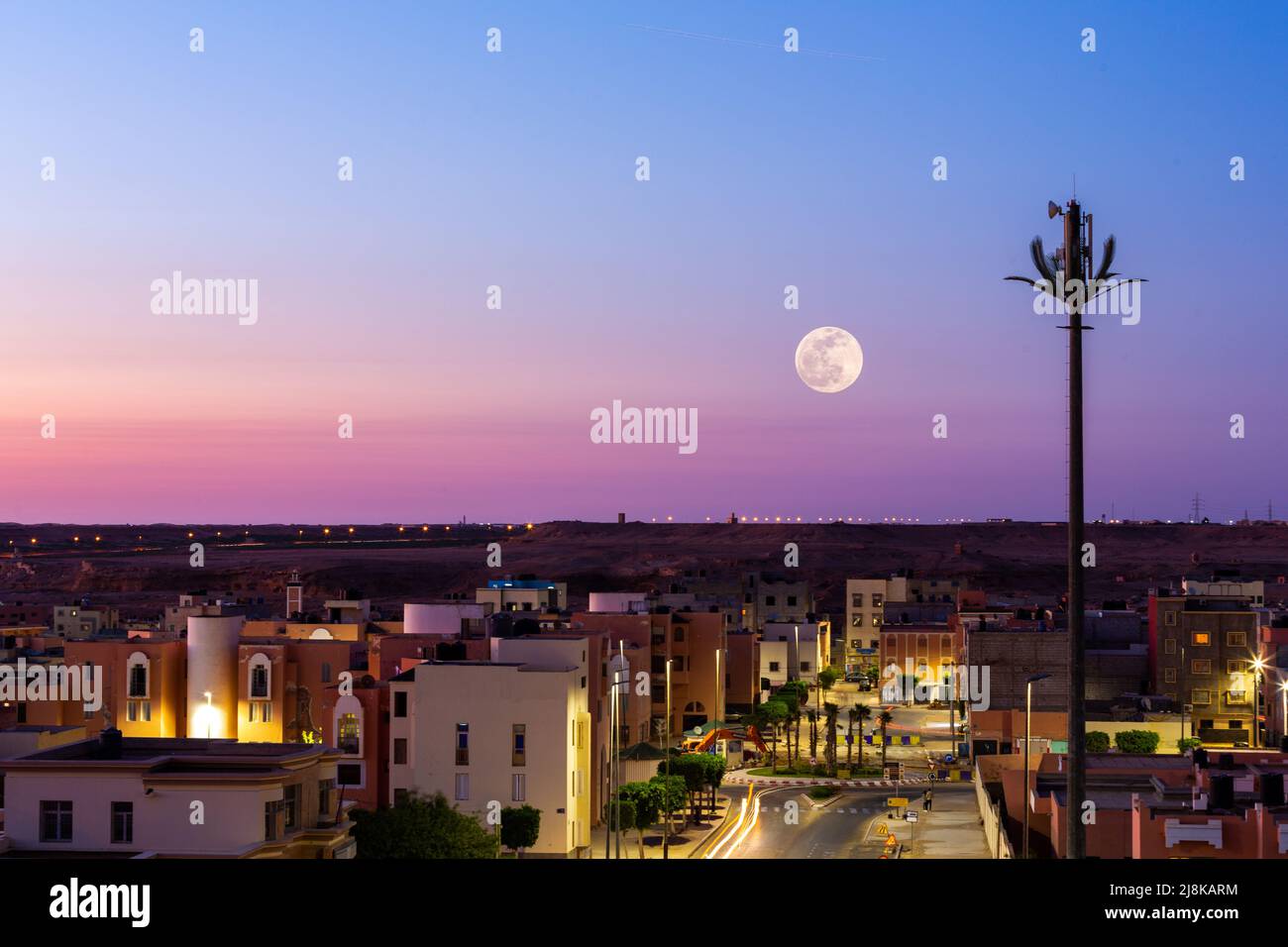 Pleine lune au-dessus d'un ciel violet dans la ville de Laayoune au Maroc Banque D'Images