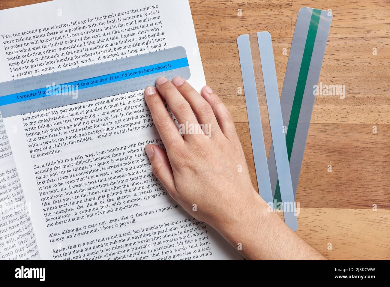 Jeune personne méconnaissable lisant un manuel à l'aide d'une superposition teintée, un outil éducatif qui aide les personnes souffrant de dyslexie à lire plus facilement Banque D'Images