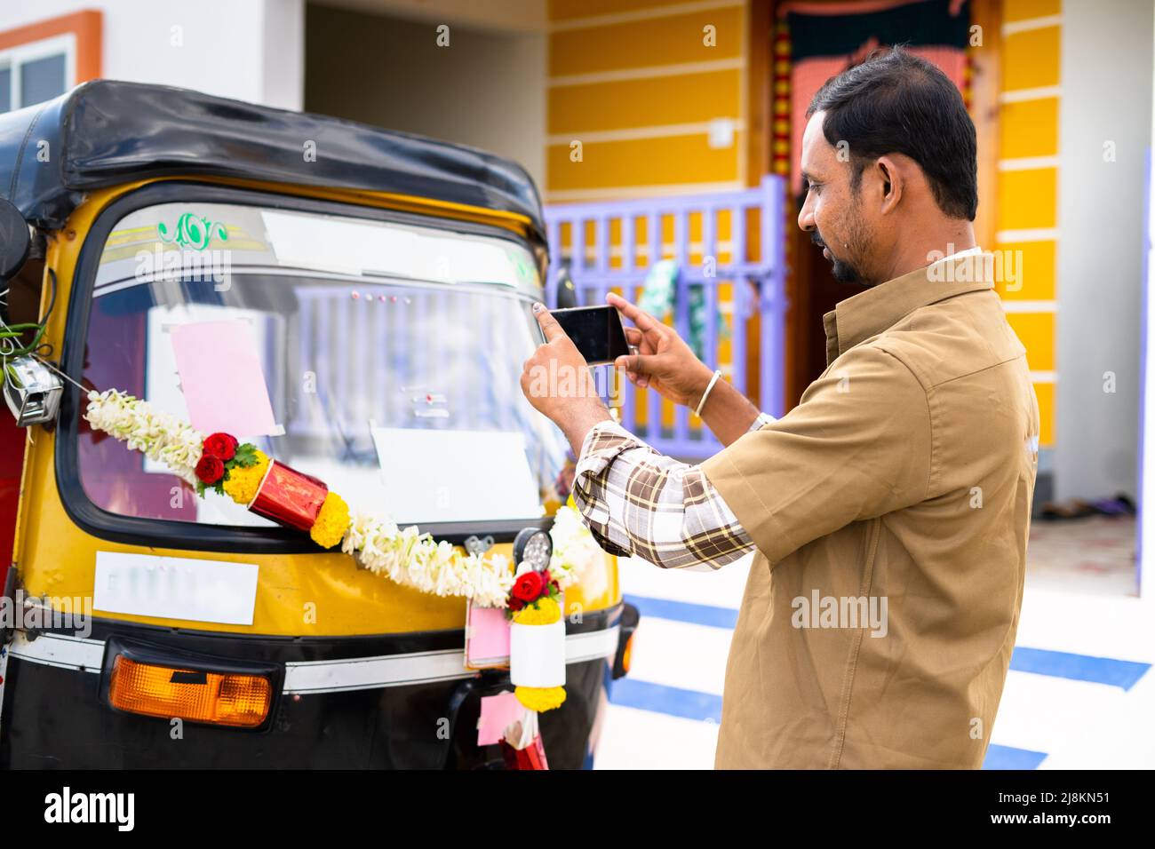 Chauffeur occupé à prendre la photo de son nouvel auto Rickshaw avant de conduire pour poster sur les médias sociaux - concept de démarrage de nouvelles petites entreprises, le transport Banque D'Images