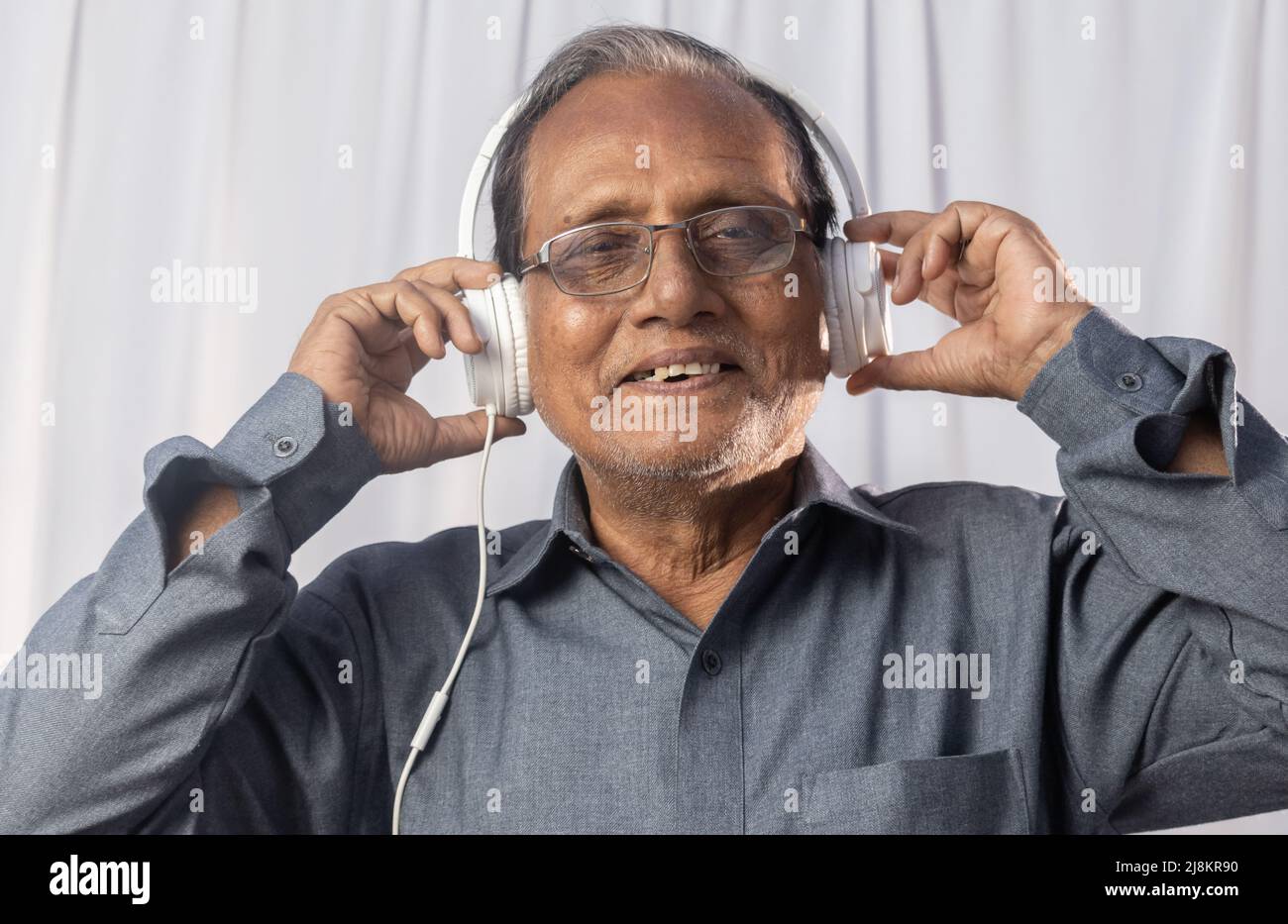 Un vieil Indien aime la musique avec un casque blanc Banque D'Images