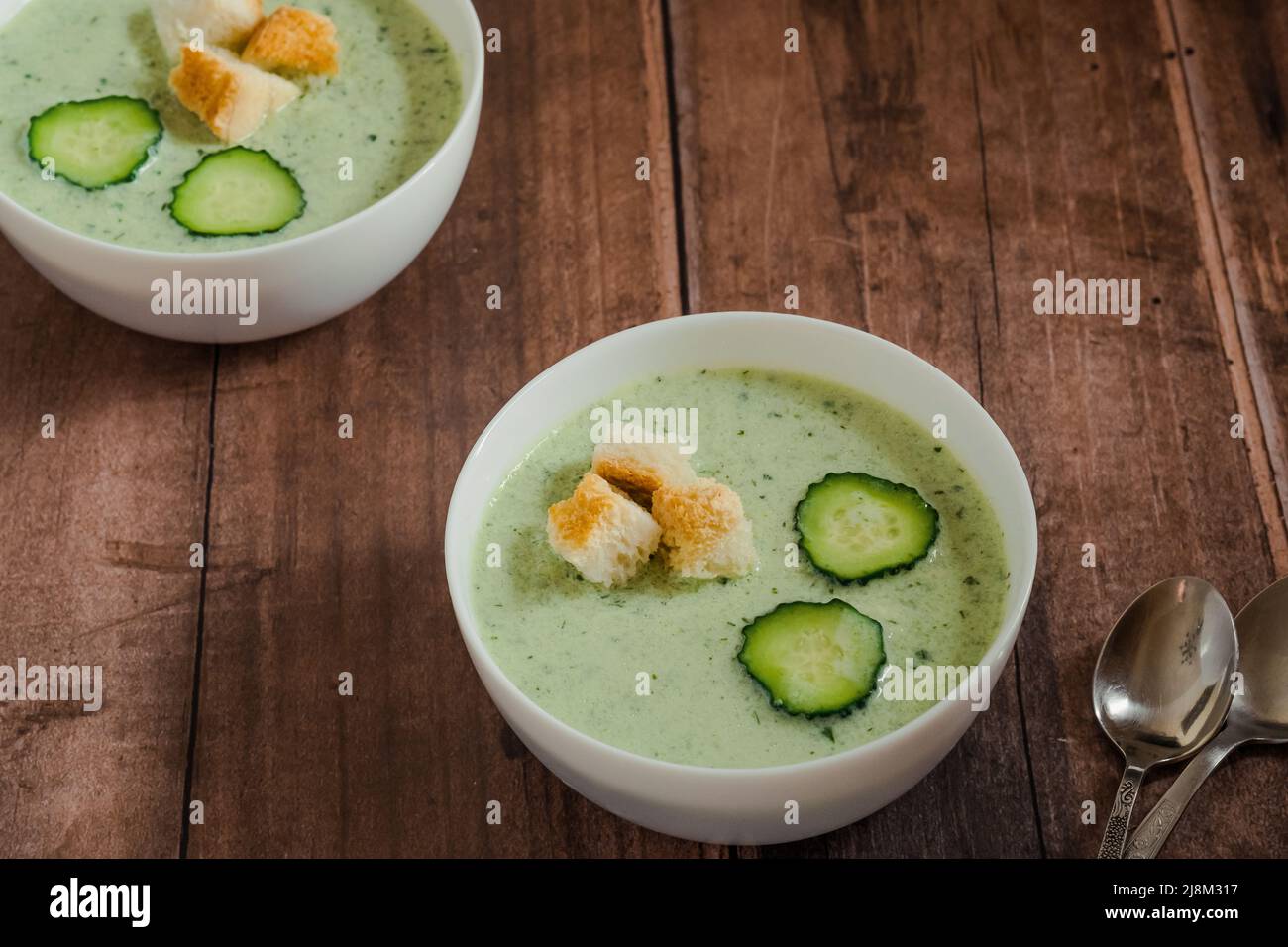 Soupe froide verte avec concombre sur une table en bois. Nourriture végétalienne saine Banque D'Images