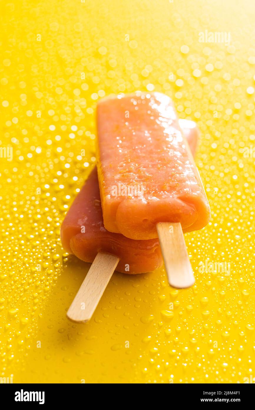 Un laque fruité. Popsicle doux sur table jaune avec gouttes d'eau. Banque D'Images