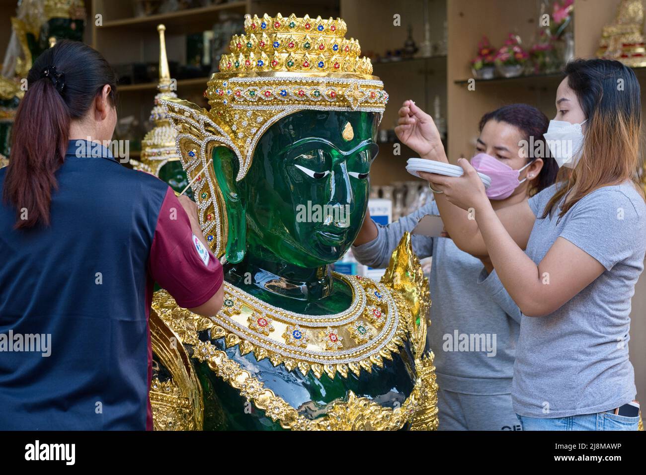 Employés dans un atelier pour les objets rituels bouddhistes à Bamrung Muang Rd., Bangkok, Thaïlande, mettant les dernières touches à une réplique du Bouddha de Jade Banque D'Images