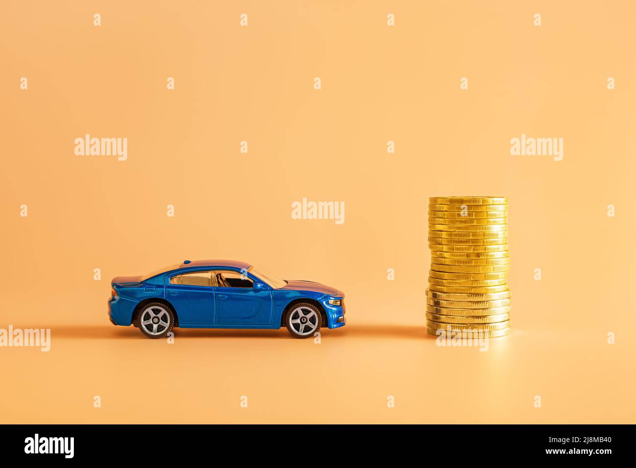 Varna, Bulgarie, 10 mai 2022. Modèle de voiture bleu et pile de pièces de monnaie dorées sur fond orange. Concepts d'économie d'argent pour une voiture, assurance automobile. Banque D'Images