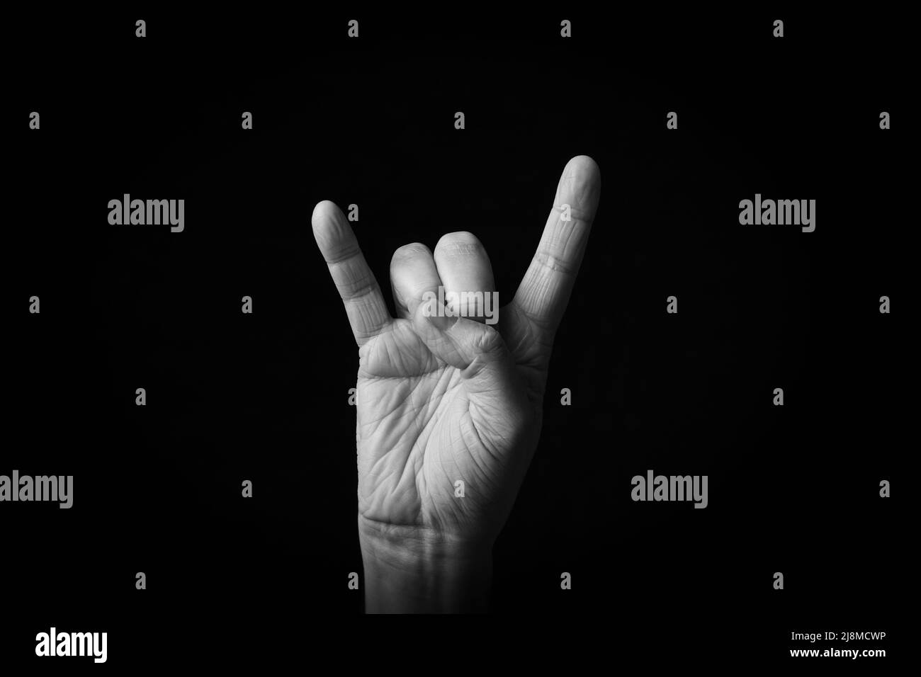 Image spectaculaire en noir et blanc du signe des cornes emoji isolé sur fond noir Banque D'Images