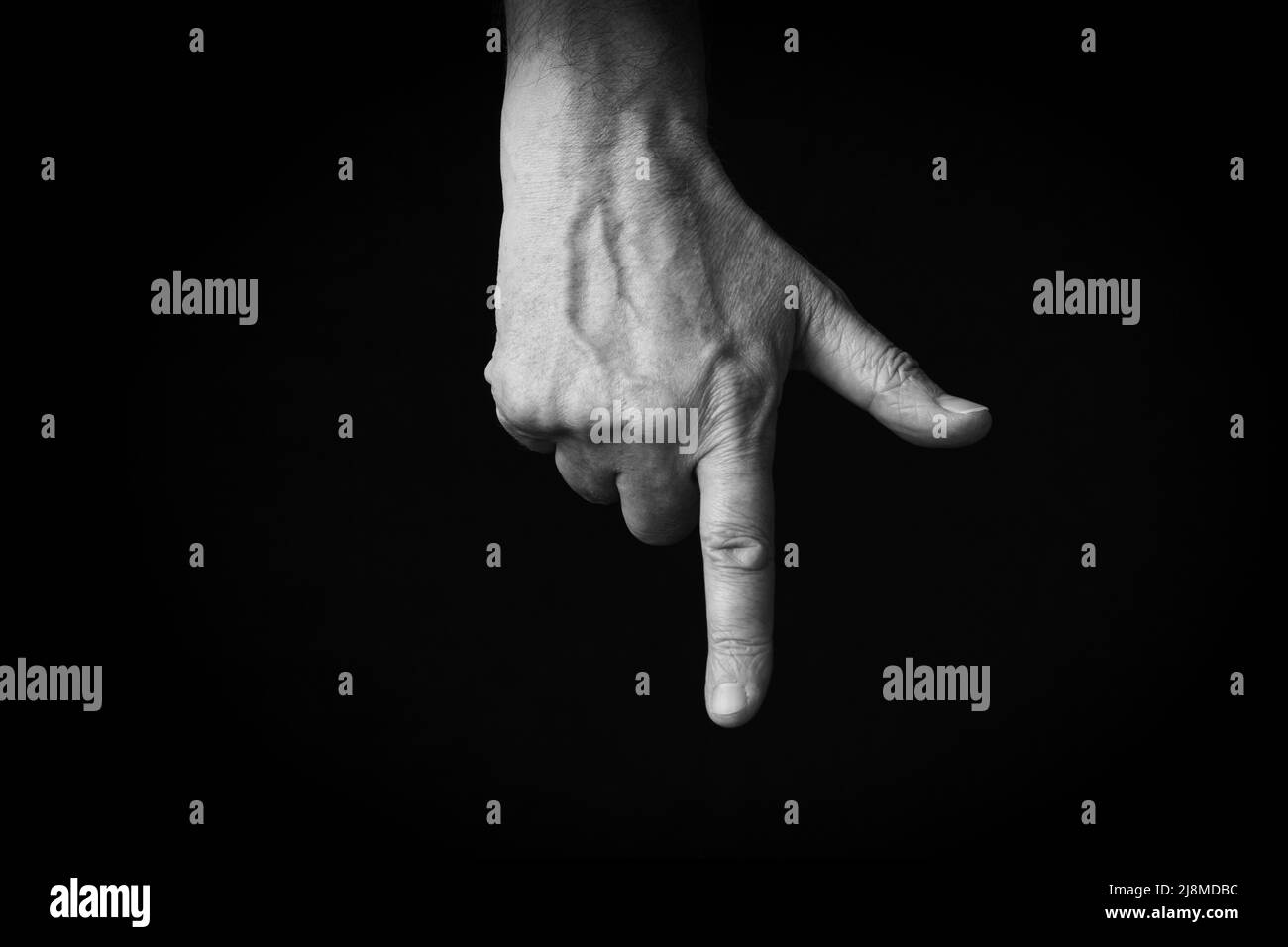 Image spectaculaire en noir et blanc de l'index de la main arrière pointant vers le bas emoji isolé sur fond noir Banque D'Images