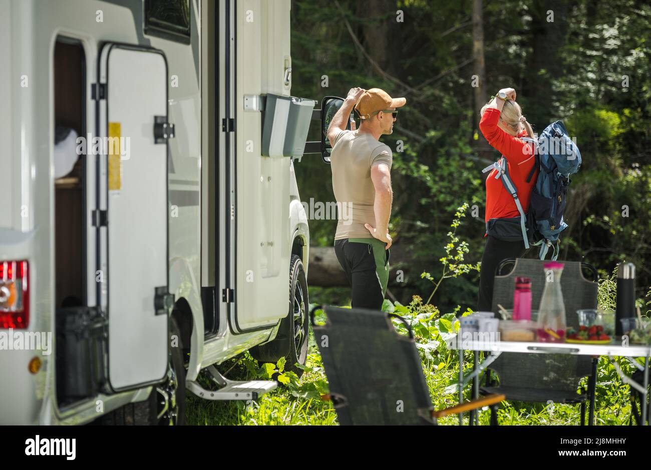 Couple caucasien séjournant à côté de leur camping-car Van et se préparant pour une randonnée d'une journée pendant leurs vacances. Banque D'Images