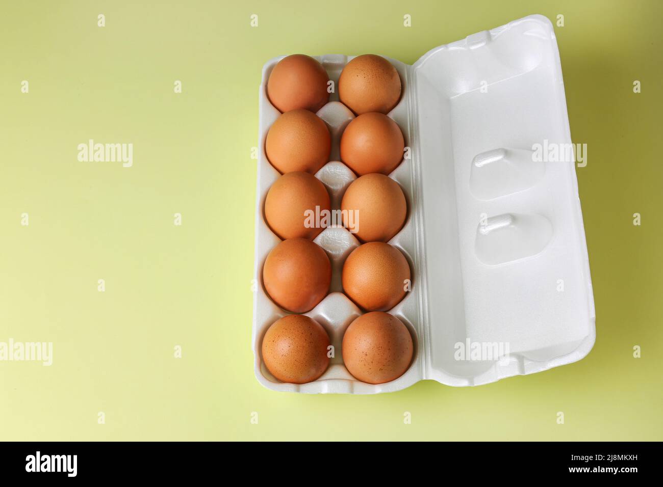 Faire dorer les œufs dans un emballage en polystyrène expansé sur un fond jaune clair isolé Banque D'Images