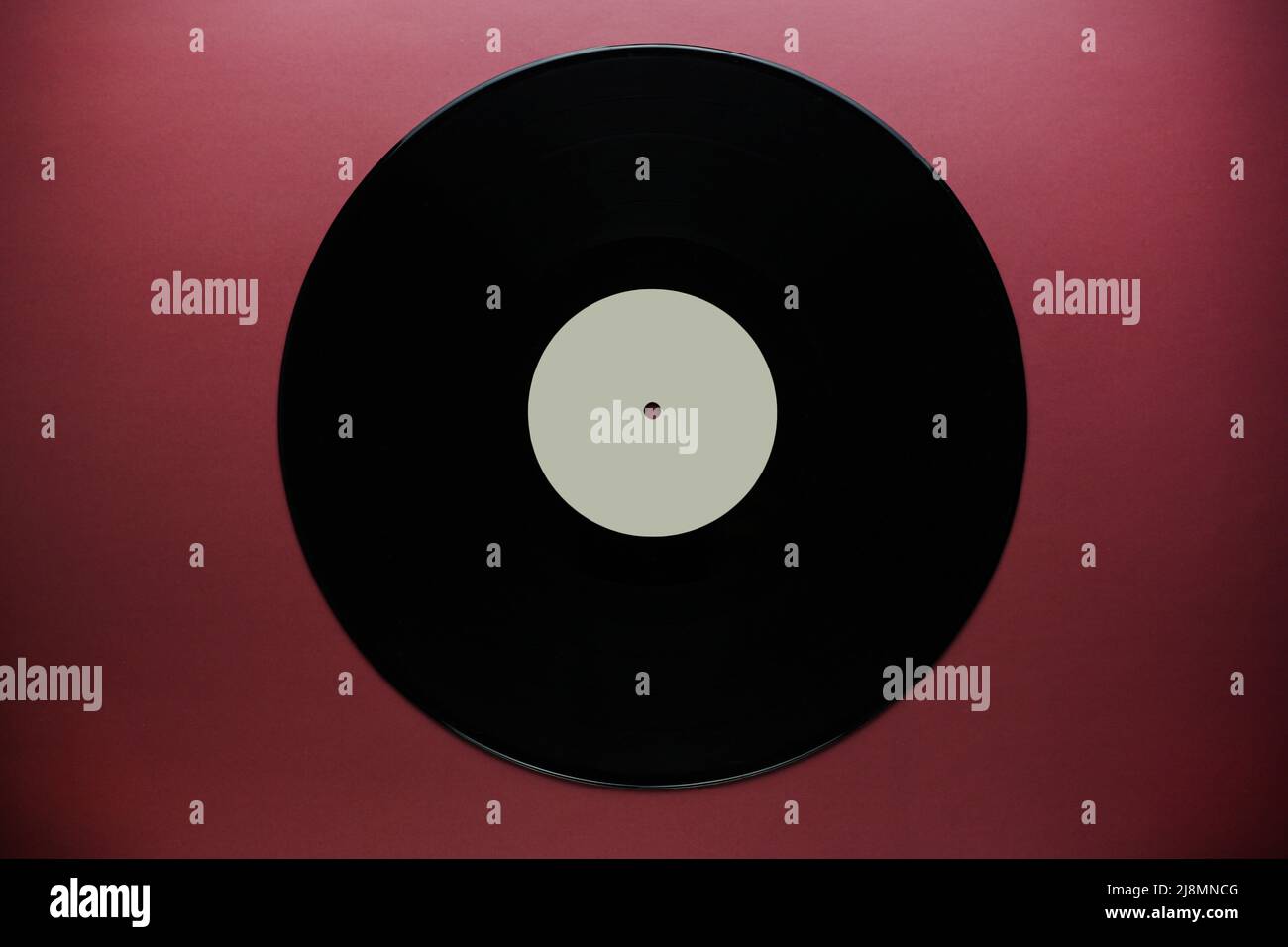 Gros plan sur un disque vinyle classique sur fond rouge bordeaux, stockage de données désuet, musique Banque D'Images