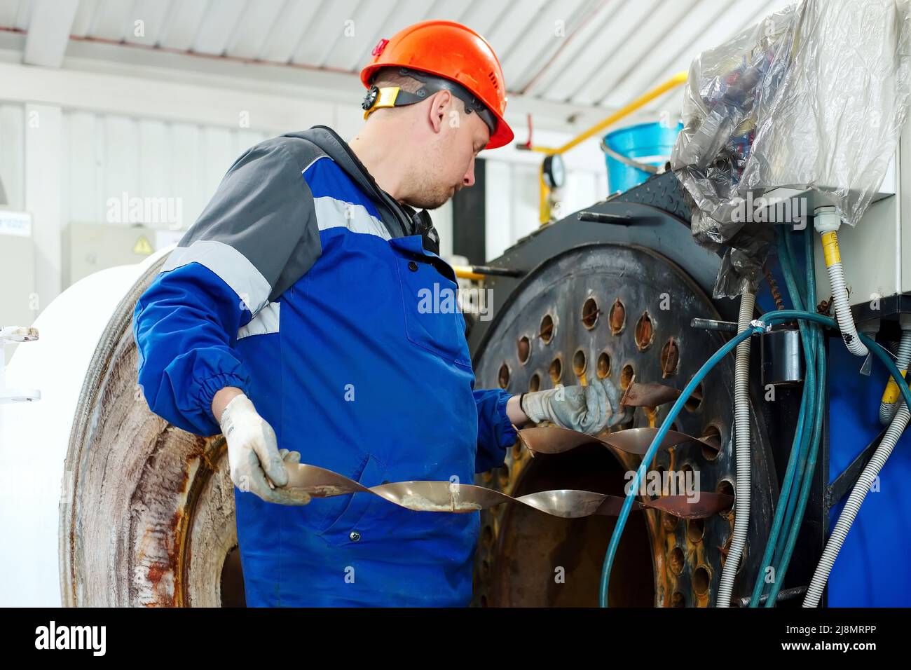 Un ingénieur en casque inspecte et répare les équipements à gaz de la chaufferie. Nettoyage et entretien de chaudière à vapeur industrielle. Banque D'Images