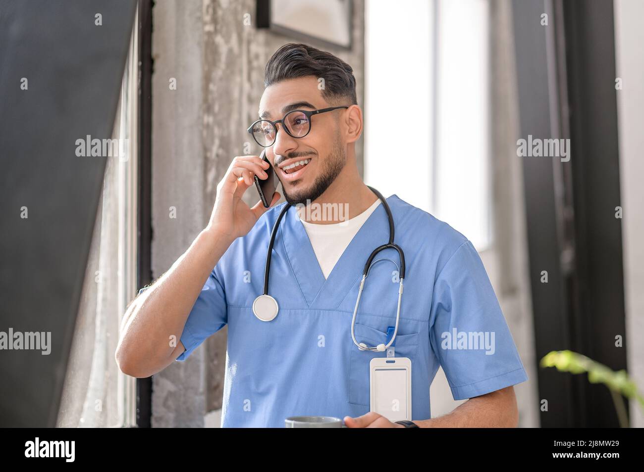Un médecin satisfait de lunettes ayant une conversation téléphonique Banque D'Images