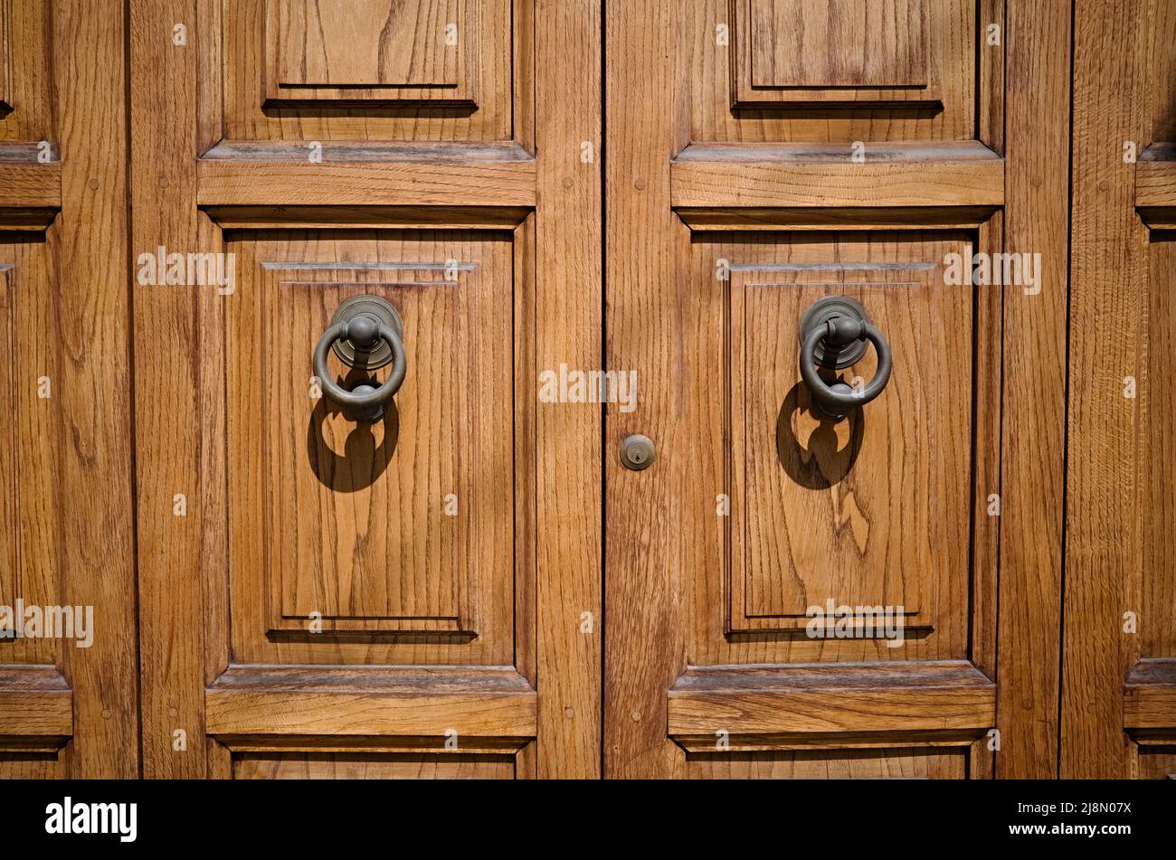Grandes portes d'entrée en bois avec poignées rondes en métal et petit trou de serrure. Portes doubles en bois massif de couleur bois naturel Banque D'Images