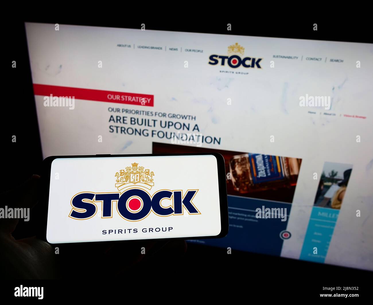 Personne tenant un téléphone portable avec le logo de la société britannique stock Spirits Group plc sur l'écran en face de la page Web d'affaires. Mise au point sur l'affichage du téléphone. Banque D'Images