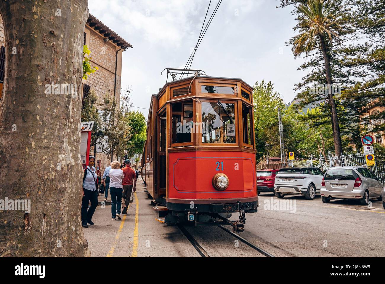 Les voyageurs qui marchent en tramway sur les voies ferrées contre les bâtiments et les voitures de la ville Banque D'Images