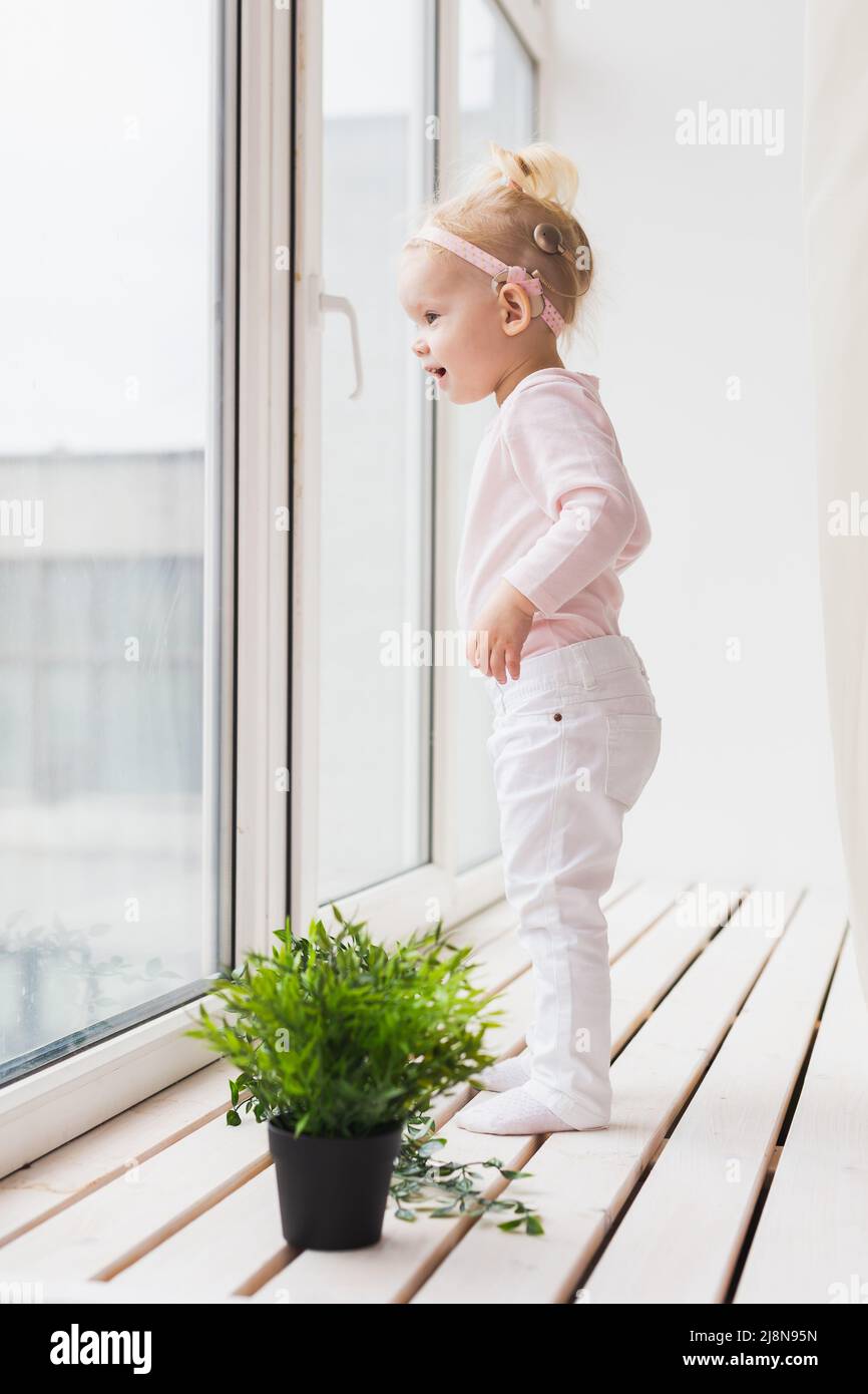 Implant cochléaire pour bébé. Un enfant sourd avec prothèse auditive joue dans le salon Banque D'Images