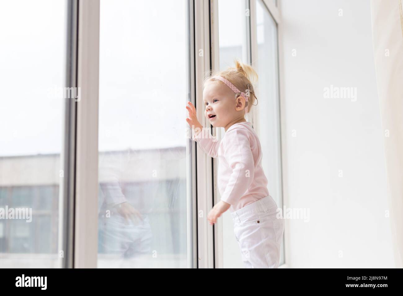 Implant cochléaire pour bébé. Un enfant sourd avec prothèse auditive joue dans le salon Banque D'Images