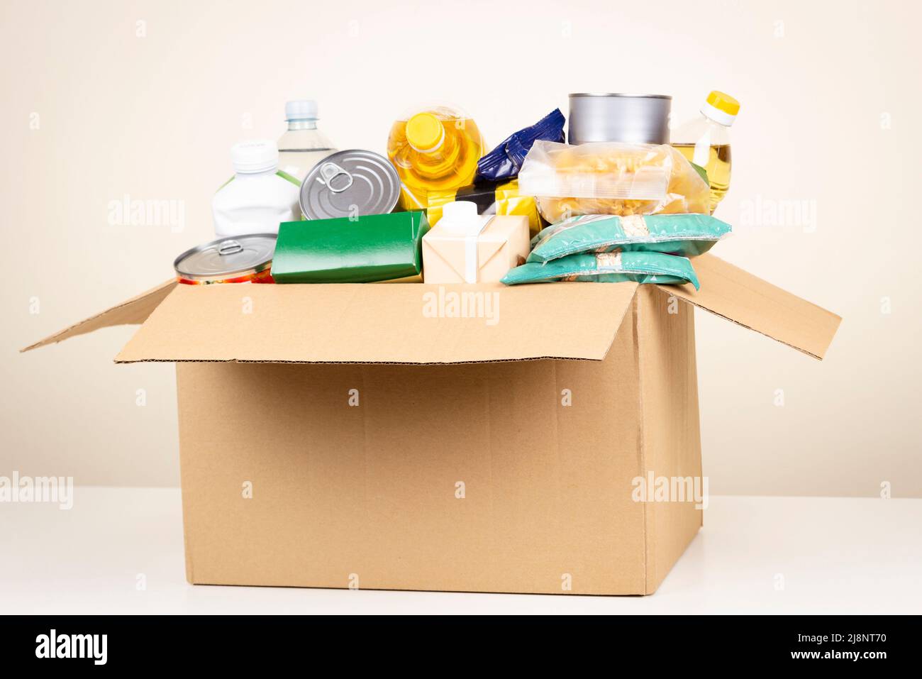 Boîte en carton avec produits d'épicerie. Faites du bénévolat pour recueillir les aliments dans la boîte de dons. Don, charité, banque alimentaire, aide aux familles pauvres, migrants Banque D'Images