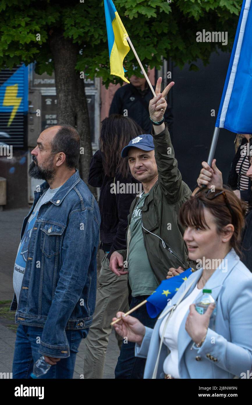Sofia, Bulgarie - 09 mai 2022 : un homme marche dans une foule avec un drapeau ukrainien de taille moyenne, levé dans la main, montrant le V-signe avec les doigts Banque D'Images