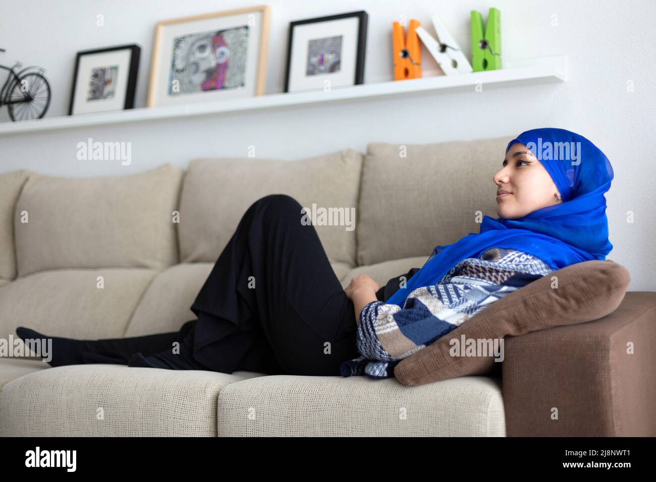 Jeune femme musulmane allongé sur un canapé à la maison. Détente et calme. Banque D'Images