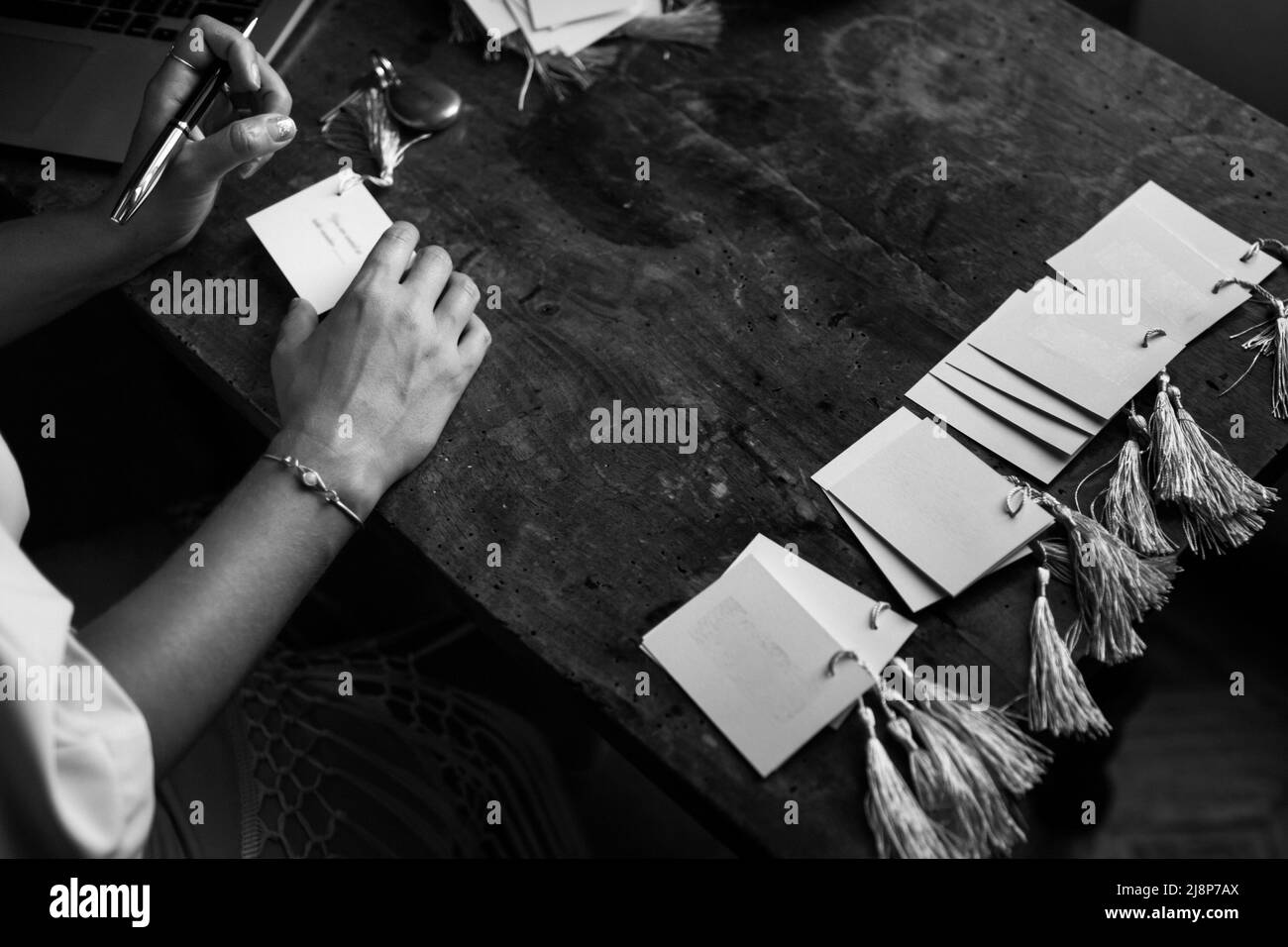 La mariée signe des cartes d'invitation de mariage sur une table en bois. Banque D'Images