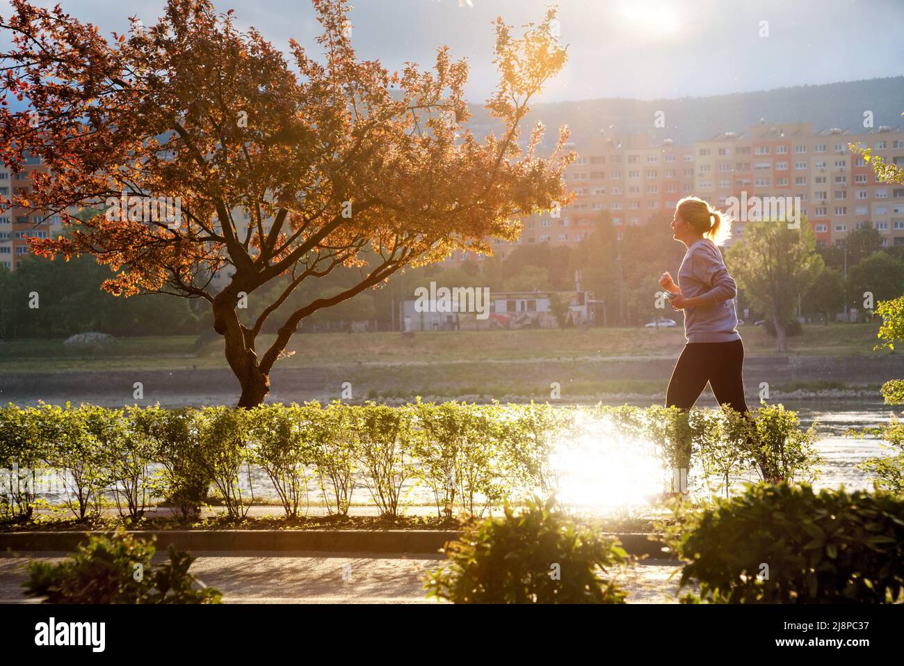 Femme qui fait du jogging dans un parc au bord de la rivière Banque D'Images