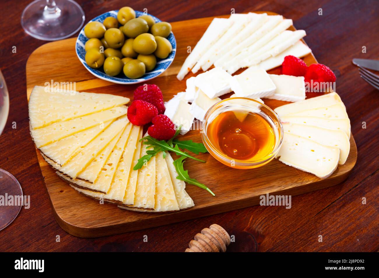 Assiette avec différents types de fromage, framboises et olives Banque D'Images