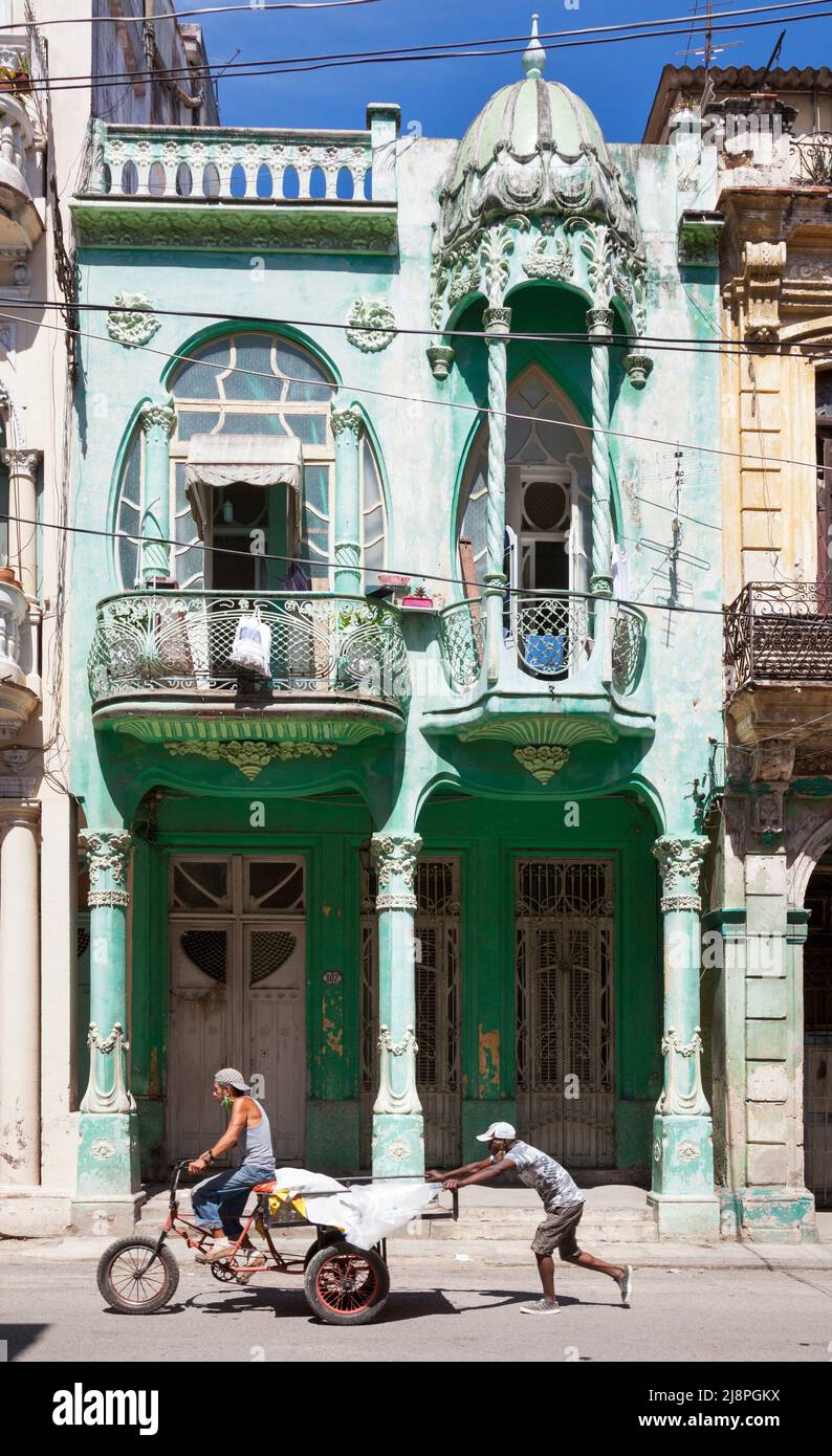 Ouvriers poussant le chariot trike devant une maison de style Art Nouveau. Architecte : Mario Rotllant i Forcará. Cárdenas, Havana Vieja, Cuba Banque D'Images