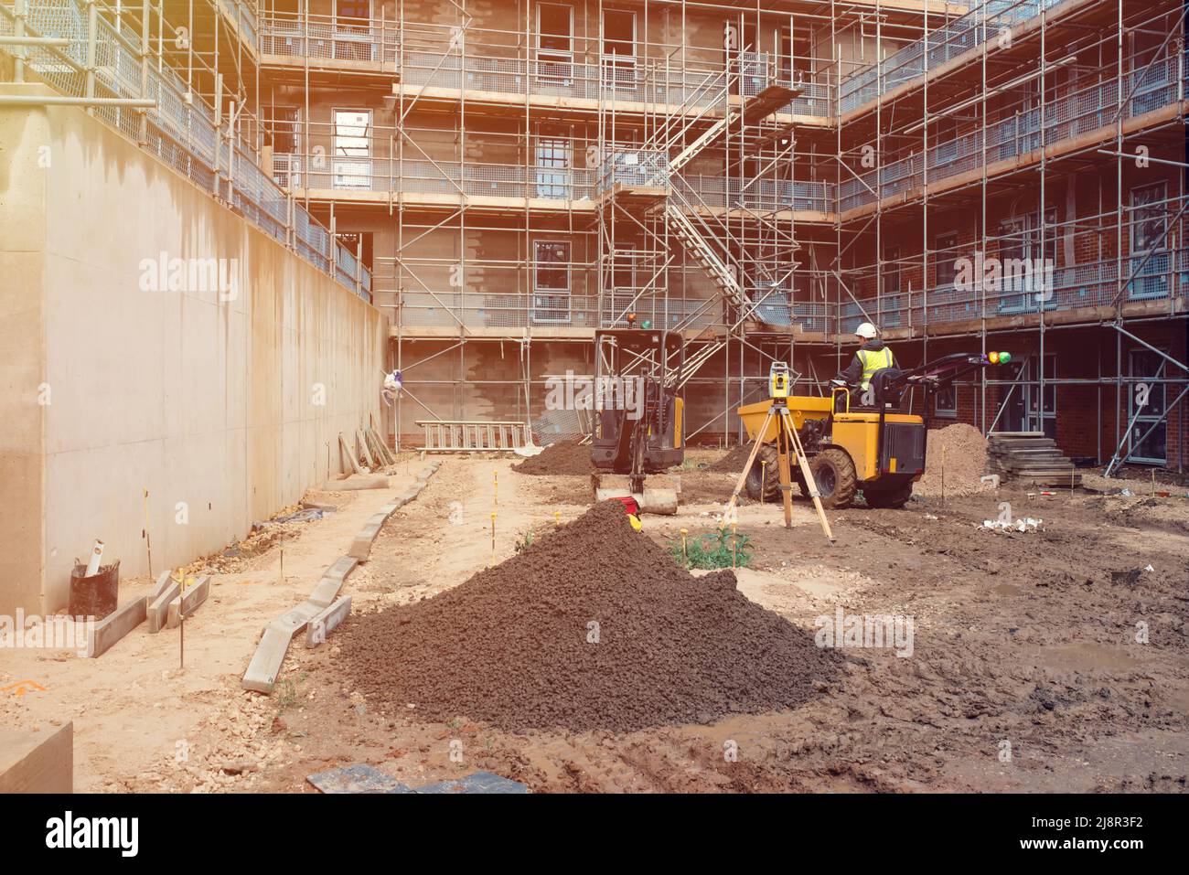 Un constructeur conduit un tombereau de chantier et une pelle hydraulique sur un nouveau chantier de construction. Équipement d'arpentage sur le chantier Banque D'Images