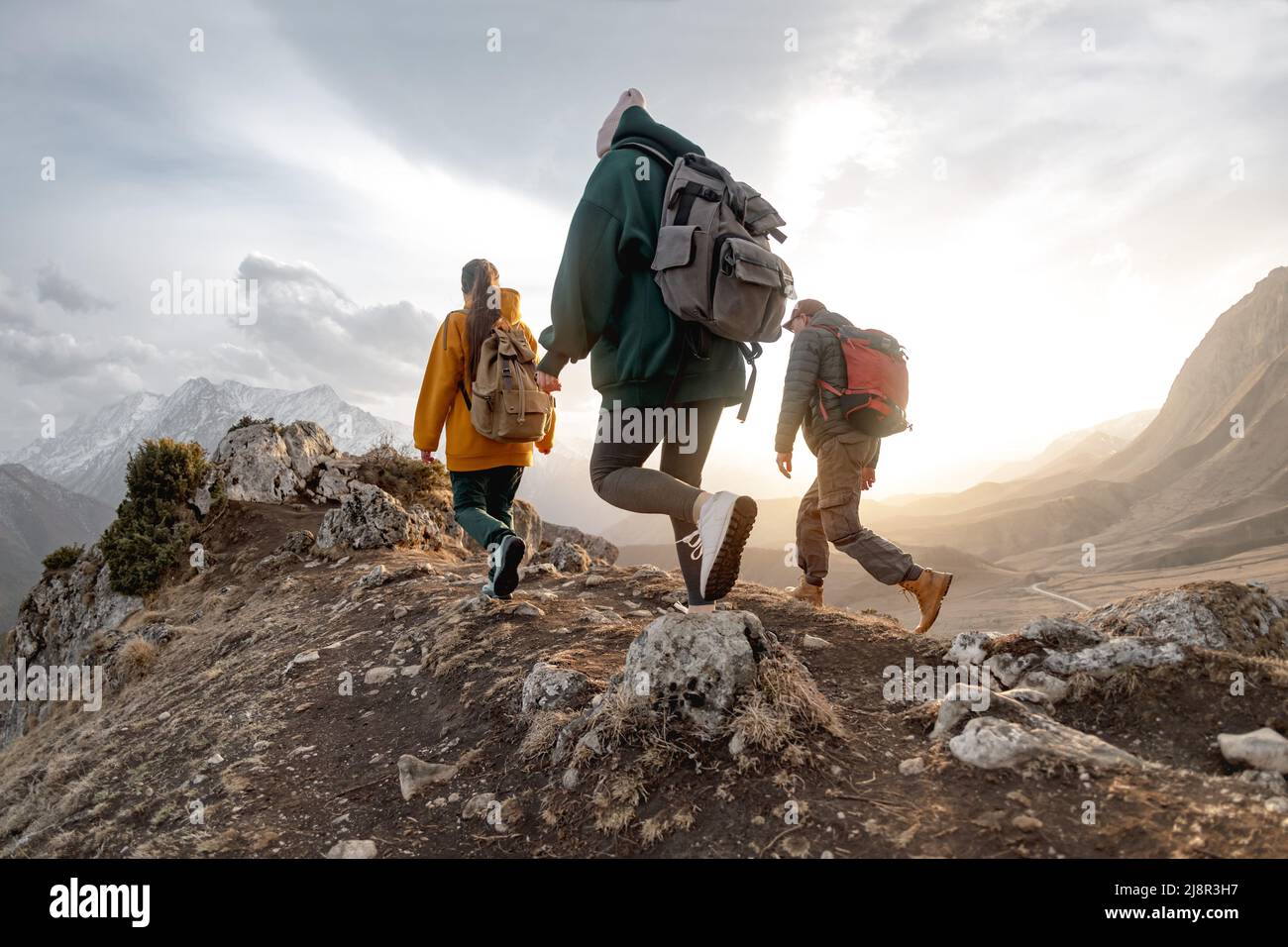 Les jeunes randonneurs avec des sacs à dos marchent dans les montagnes au coucher du soleil Banque D'Images