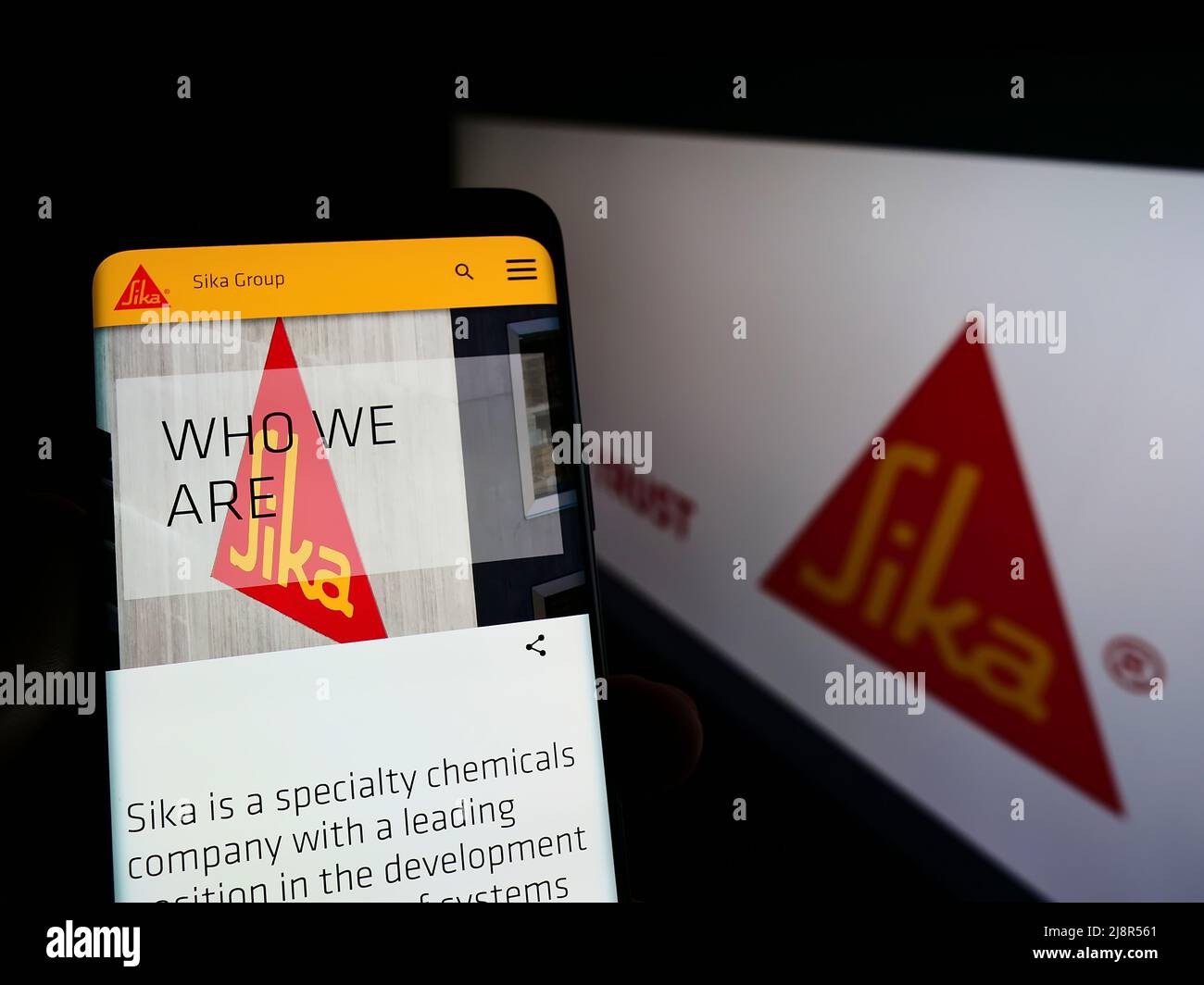 Personne tenant le téléphone portable avec la page web de la société suisse de produits chimiques spécialisés Sika AG sur l'écran devant le logo. Concentrez-vous sur le centre de l'écran du téléphone. Banque D'Images