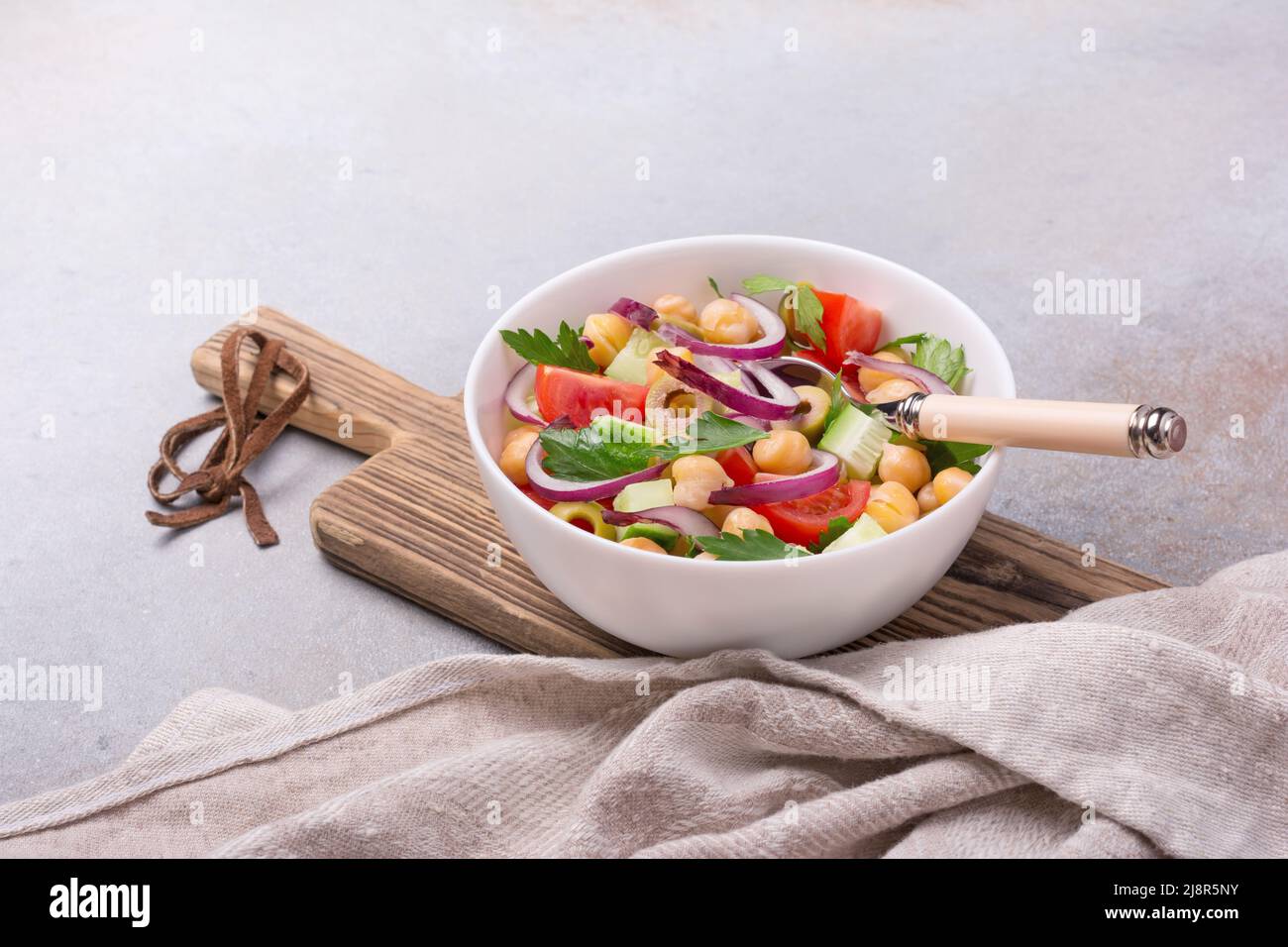 Nourriture végétalienne saine et savoureuse. Salade de pois chiches avec laitue, tomates cerises, oignons, concombres et olives vertes sur fond de béton gris Banque D'Images