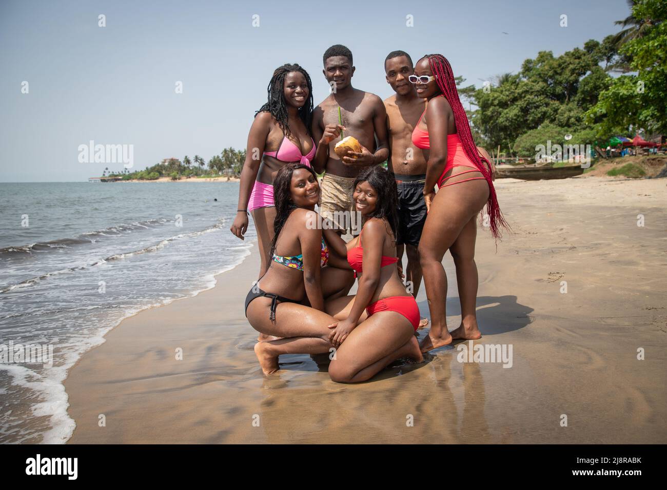 Groupe de jeunes hommes et femmes africains à la plage posant et s'amusant. Ensemble. Banque D'Images