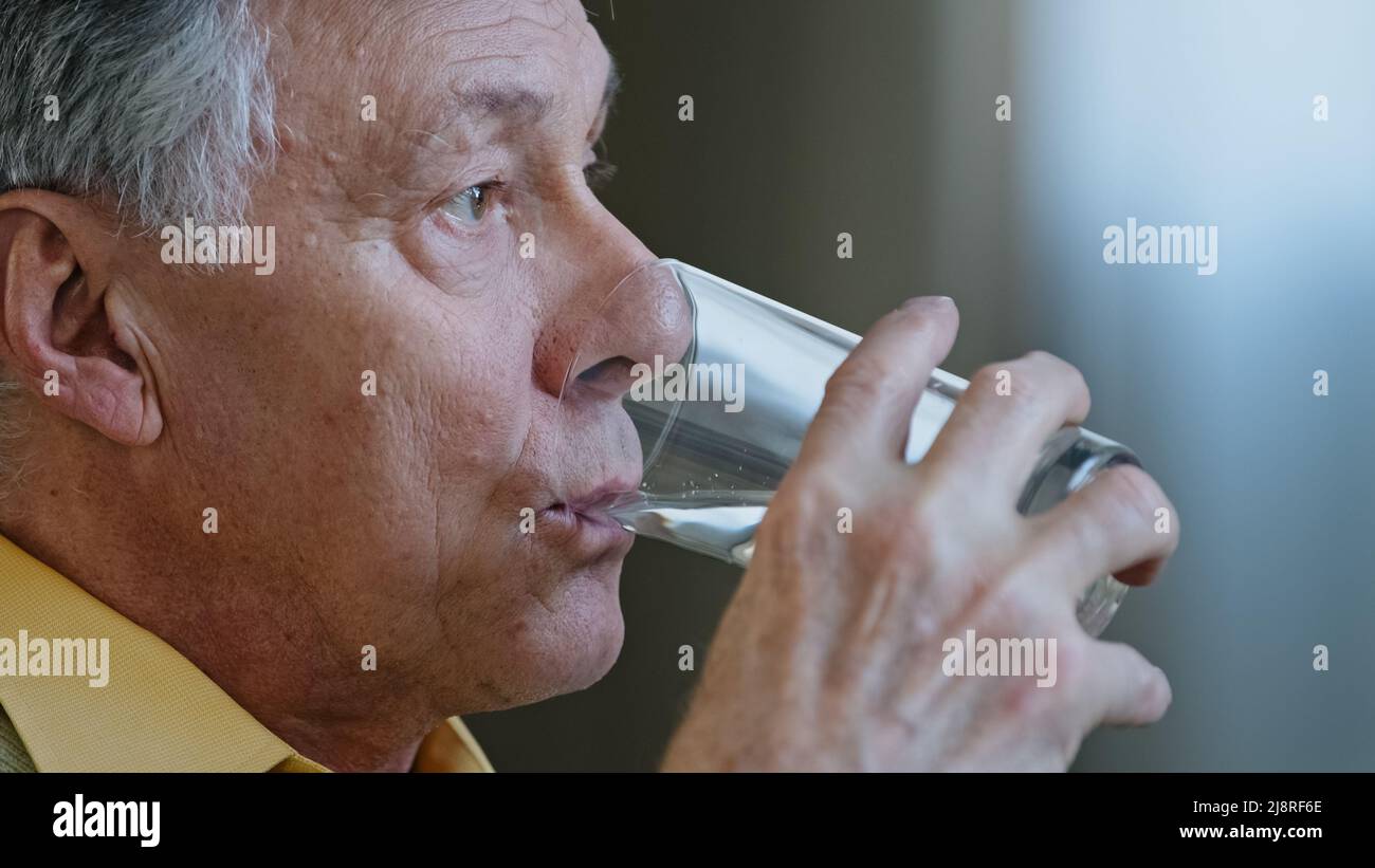 Gros plan ancien âgé mature Caucasien regardant loin penser tenir un verre d'eau propre boissons H2O soins de santé saines habitudes grand-père dr Banque D'Images