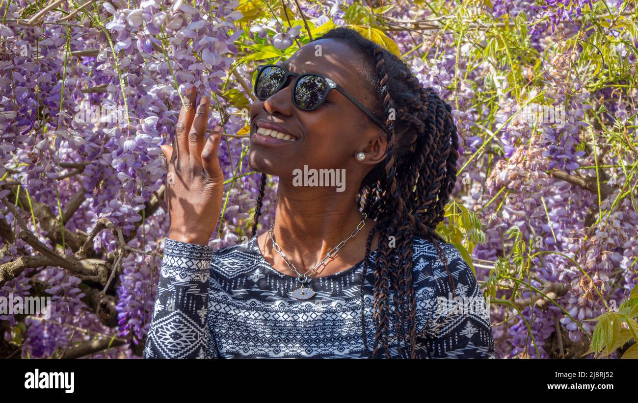 Portrait d'une jeune femme heureuse qui sent des fleurs violettes Banque D'Images