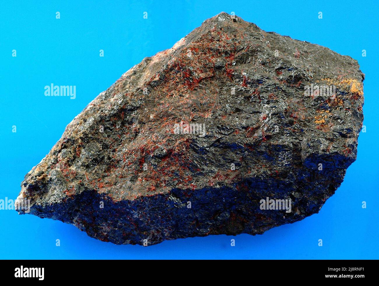 Franklinite, zinciter, willémite et calcite de Franklin, New Jersey, Etats-Unis. Ce spécimen provient de Franklin, dans le New Jersey, une localité de renommée mondiale qui a produit de nombreuses espèces minérales autrefois inconnues et exotiques. Il comprend principalement de la franklinite noire (oxyde de fer de zinc) et du zinciter rouge (oxyde de zinc). Il y a aussi du saulémite vert clair mineur (silicate de zinc) et du calcite blanc mineur (carbonate de calcium) (mais il est difficile du voir le long du bord gauche de l'échantillon). Franklin a toujours été une importante zone minière, et trois de ces minéraux sont des minerais de zinc. Banque D'Images