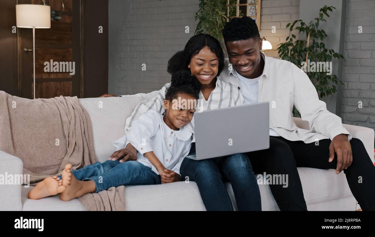 Bonne famille africaine et mignon enfant fille fille en utilisant un ordinateur portable regardant l'écran d'ordinateur appréciant regarder drôle de médias sociaux vidéo ayant en ligne Banque D'Images