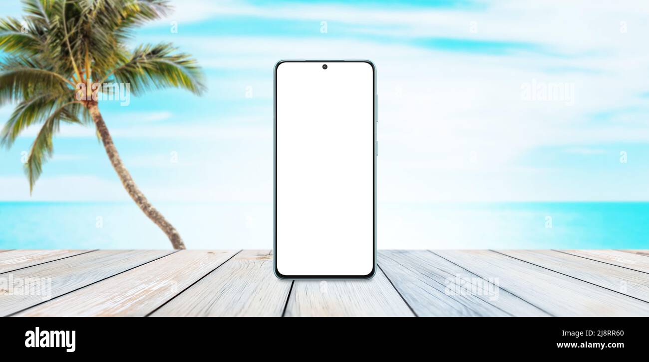 Téléphone maquette sur table en bois avec plage, palmier et mer en arrière-plan. Concept de promotion de voyage d'été Banque D'Images