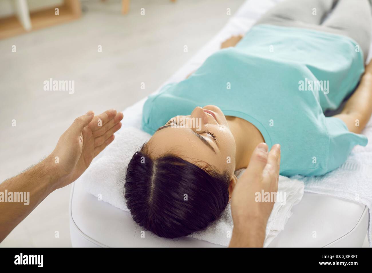 La femme subit une thérapie alternative pendant la séance de reiki dans la salle de massage moderne. Banque D'Images